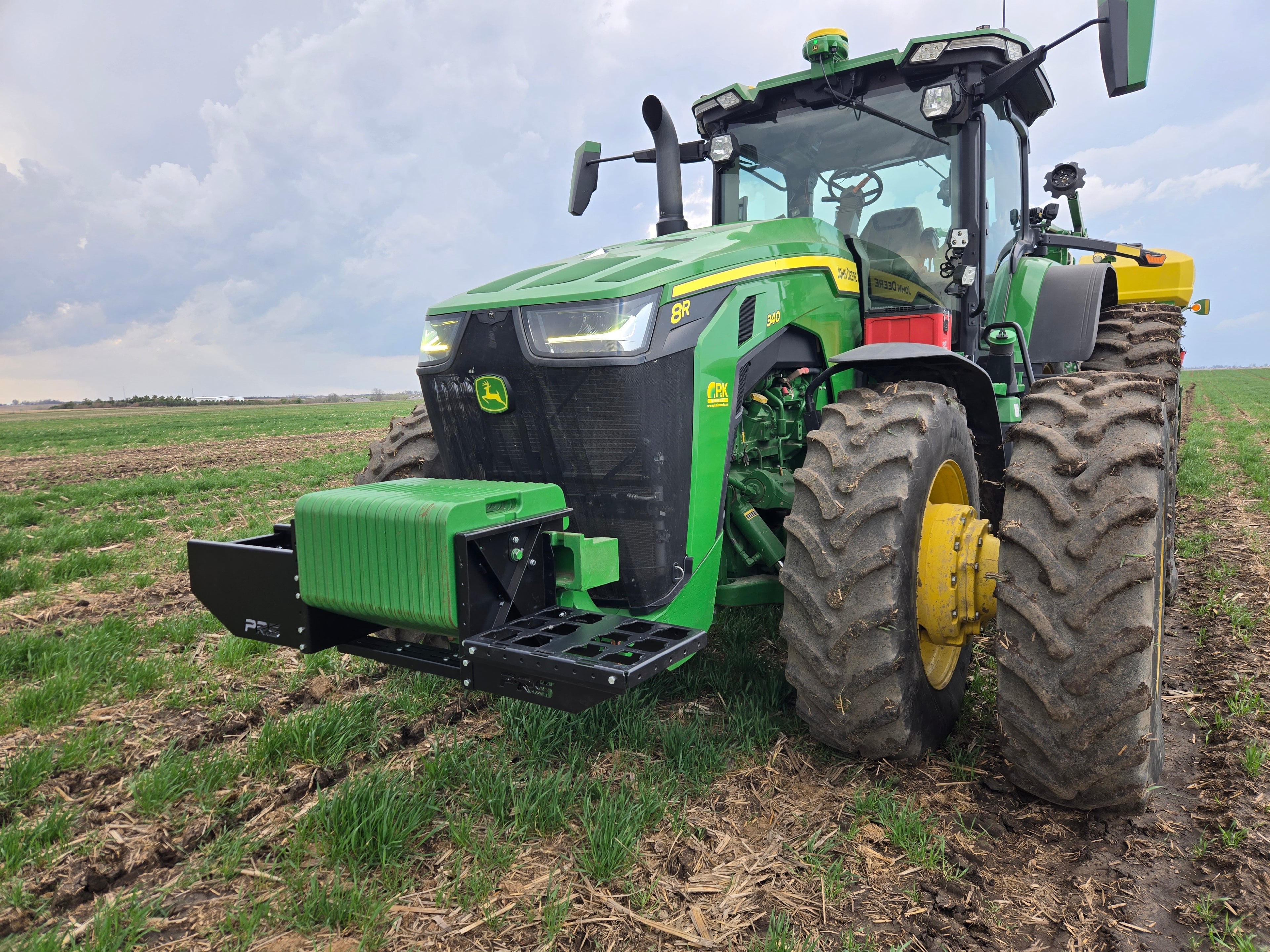 Green tractor in a field with a cloudy sky
