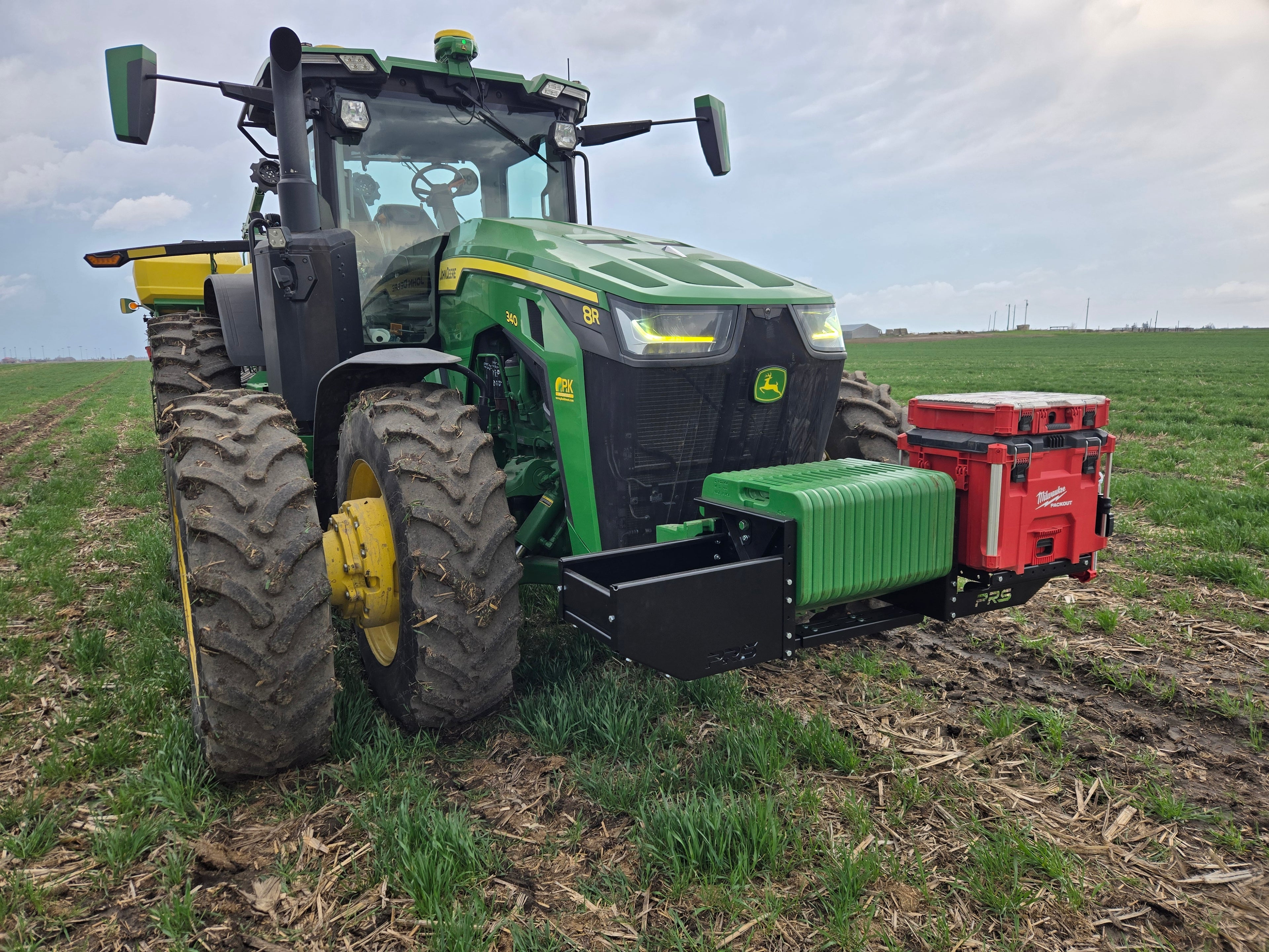 Green tractor with a red implement in a field